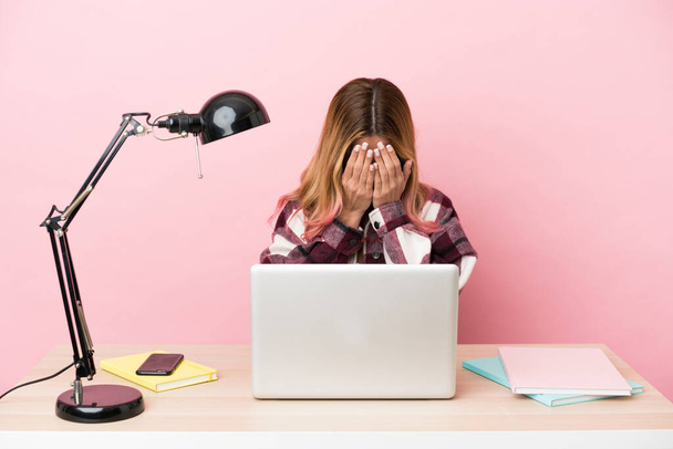 若いです学生女性で職場でノートパソコン上ピンクの背景とともに疲れと病気の式 - 写真・画像