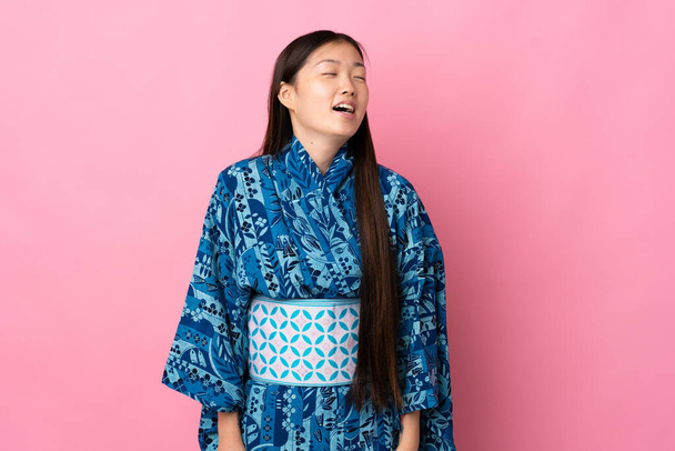 Menina chinesa jovem vestindo quimono sobre fundo isolado rindo - Foto, Imagem