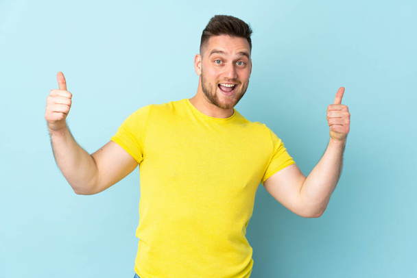 Russian handsome man isolated on blue background giving a thumbs up gesture - Photo, Image