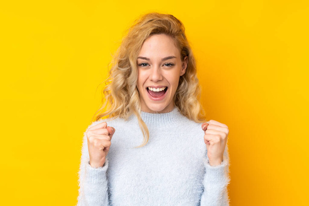 Young blonde woman isolated on yellow background celebrating a victory in winner position - Фото, зображення