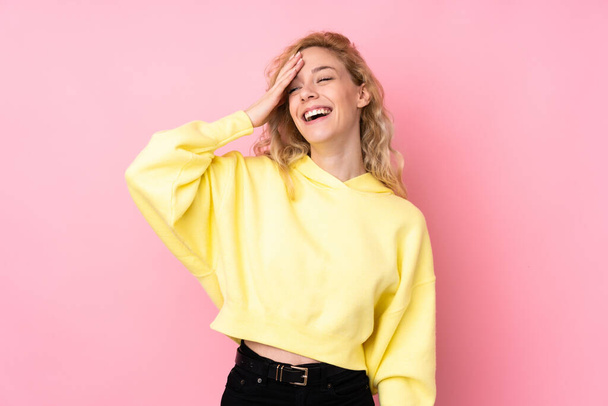 Junge blonde Frau trägt Sweatshirt auf rosa Hintergrund und lächelt viel - Foto, Bild