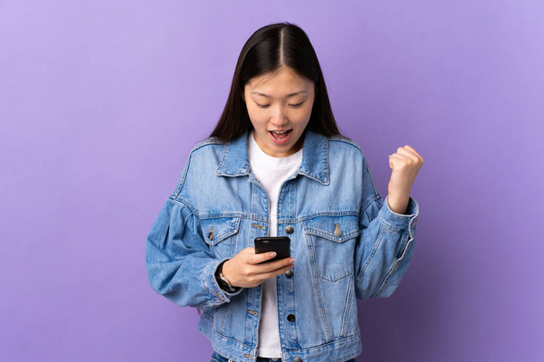 Joven chica china sobre aislado púrpura fondo sorprendido y enviando un mensaje - Foto, imagen