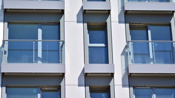 Osake- ja kerrostalo symmetrisellä modernilla arkkitehtuurilla. Yksityiskohta moderni asuin- tasainen kerrostalo ulkoa. Sirpale uutta ylellisyyttä talon ja kodin monimutkainen.  - Valokuva, kuva