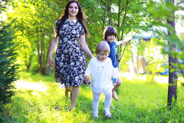 Молода велика родина на літній ранковій прогулянці. Красива мати з дітьми грає в парку
. - Фото, зображення