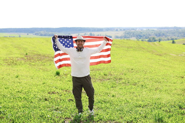 Άνθρωπος κυματίζει αμερικανική σημαία στέκεται στο γεωργικό τομέα αγρόκτημα, διακοπές, πατριωτισμός, υπερηφάνεια, ελευθερία, πολιτικά κόμματα, μετανάστης - Φωτογραφία, εικόνα