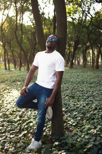 A young black man in park. Outdoor portrait of traveler. Portrait of a young african man outdoors. Outdoors portrait concept - Photo, Image