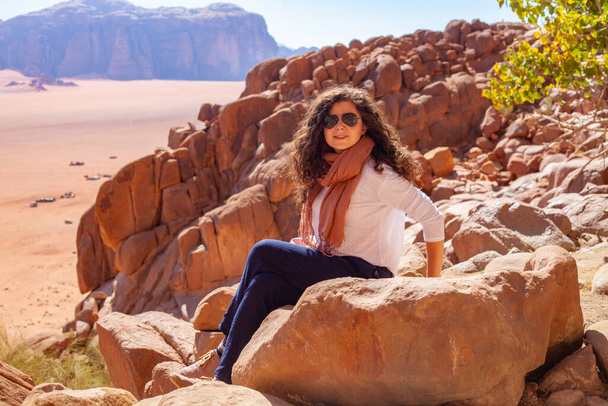 A beautiful caucasian female with curly hair posing on red sandstone cliffs - Foto, imagen