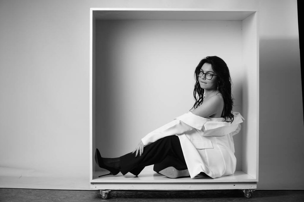 сексуальна красива брюнетка в нижній білизні і модні дзвони штани позують в декоративній коробці в студії на білому тлі
  - Фото, зображення