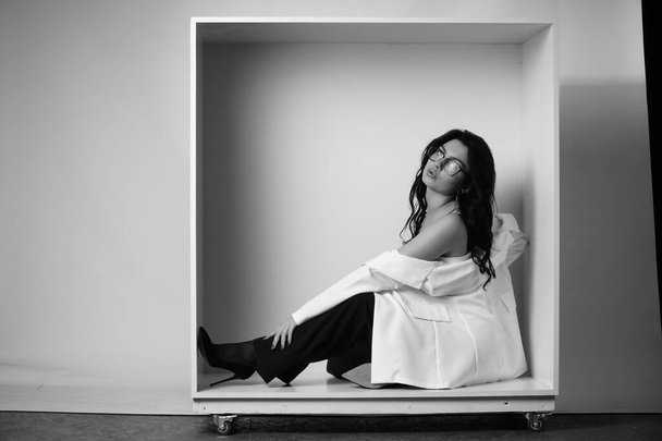 sexy beautiful brunette woman in lingerie and trendy bell bottoms pants posing in decorative box at studio on white background  - Fotoğraf, Görsel