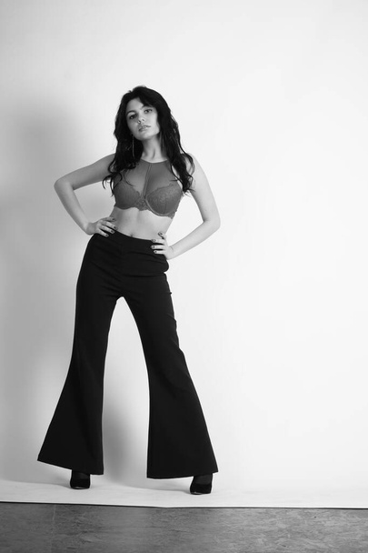 sexy beautiful brunette woman in lingerie and trendy bell bottoms pants posing at studio on white background  - Fotó, kép