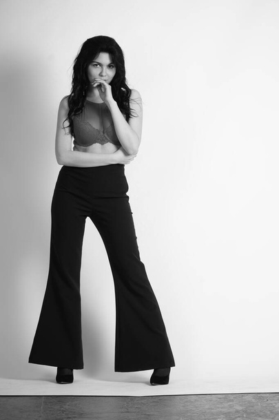seksikäs kaunis brunette nainen alusvaatteet ja trendikäs bell pohjat housut poseeraa studiossa valkoisella taustalla  - Valokuva, kuva