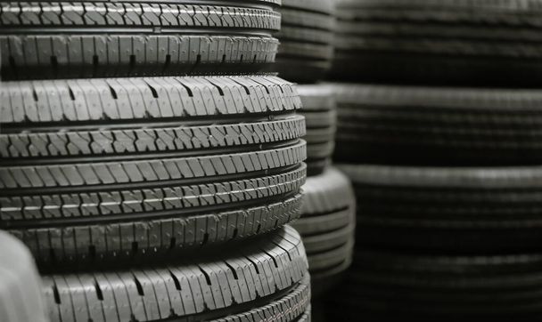 Montón de neumáticos apilados en el almacén esperando para transportar a los distribuidores, nuevo producto de neumáticos de automóviles en el fondo de fábrica de fabricación - Foto, imagen
