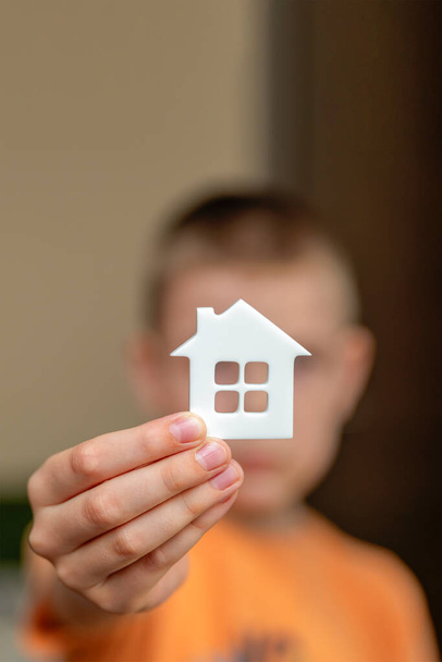 Детский дом, дети в приюте. Ребенок держит маленькую фигурку в форме дома крупным планом. Усыновление. Баннер, место для текста - Фото, изображение
