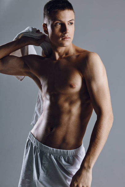 een man met een opgeblazen romp met een handdoek op zijn schouder bodybuilder fitness  - Foto, afbeelding