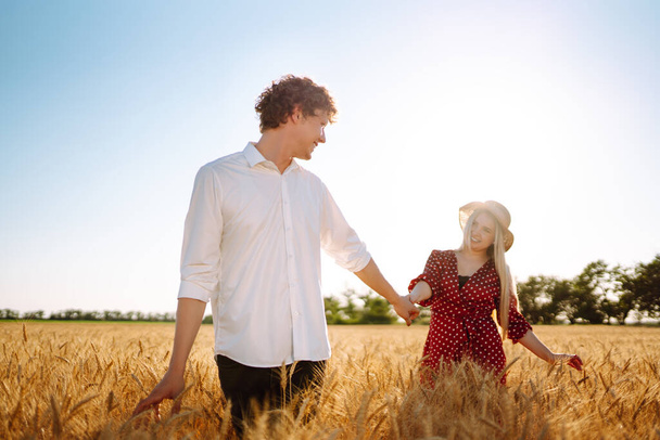 Loving couple in the in a wheat field. Enjoying time together. The concept of youth, love and lifestyle. - Photo, image