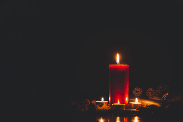 Vela roja con fuego contra luces desenfocadas en la oscuridad con bokeh dorado en el fondo oscuro - Foto, imagen
