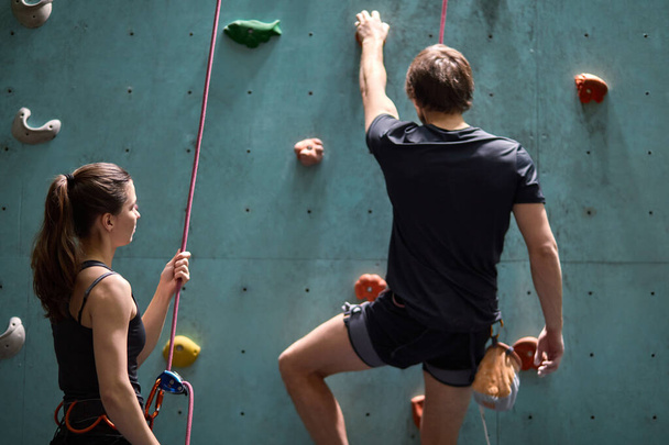 Female instructor giving instructions to man on wall climbing, learning the art of rock climbing - Foto, Bild