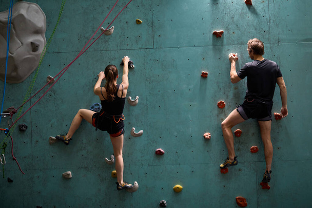 Rear view on couple climbers. Extreme indoor climbing. Strong woman and man - Fotoğraf, Görsel