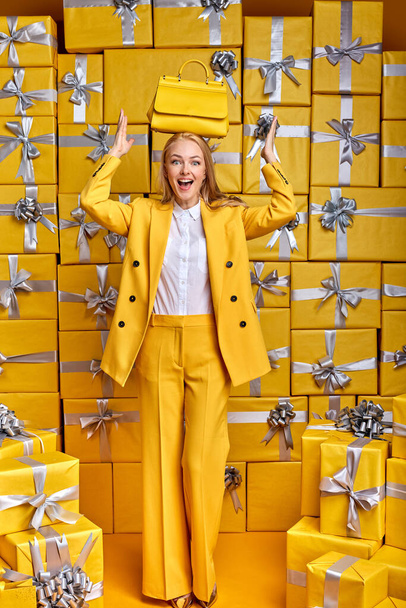 cheerful woman shopping buy new handbag wearing stylish outfit in yellow party suit - Foto, afbeelding
