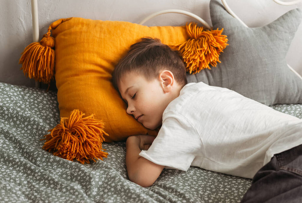 El niño duerme sobre una almohada en la cama durante el día. Dormir durante el día - Foto, imagen