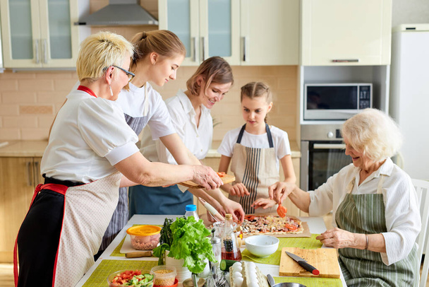Side view on friendly women and kids taking ingredients for pizza, preparing meal - Foto, imagen