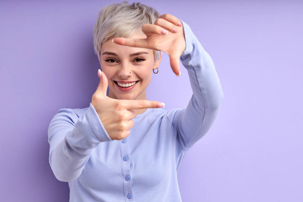 Photography concept. Joyous female smiling, making shape of square from fingers - Foto, Imagen