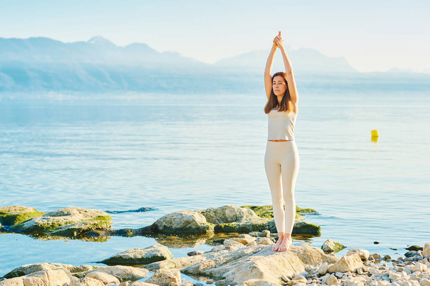 Belle femme en bonne santé pratiquant des exercices de yoga à l'extérieur près du magnifique lac de montagne  - Photo, image