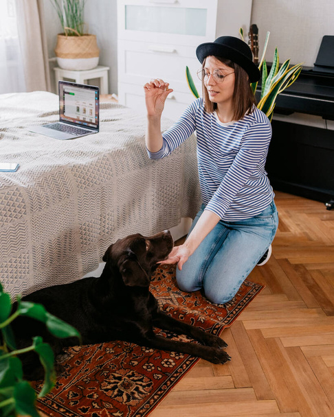 European hipster woman trains dog in her home. dog training, owner-animal communication - Valokuva, kuva