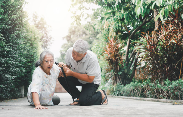 Asian senior woman falling down on lying floor at home after Stumbled at the doorstep and Crying in pain and her husband came to help support. Concept of old elderly insurance and health care - Photo, Image