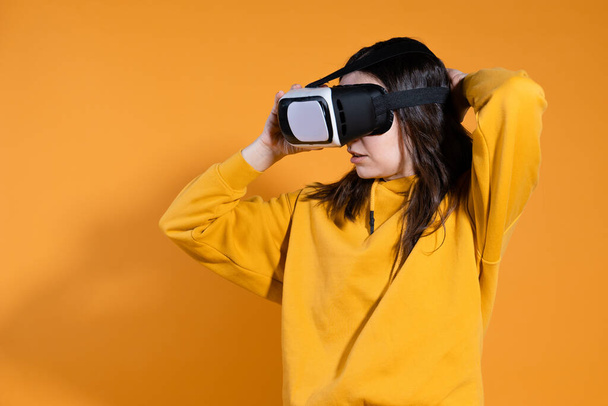 young woman with a virtual reality device on a yellow background. - Foto, imagen