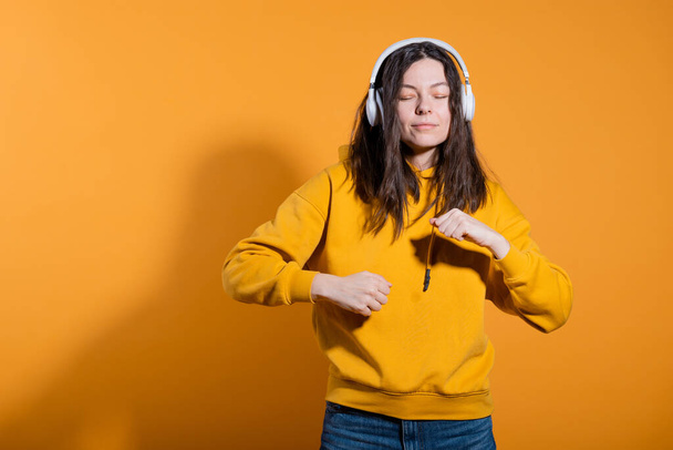 Music lovers enjoy music. A young woman in a yellow hoodie with white wireless headphones, - Foto, afbeelding
