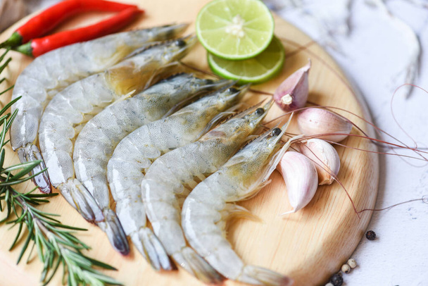 Rauwe garnalen op houten bord, Verse garnalen zeevruchten met kruiden en specerijen klaar voor gekookt voedsel  - Foto, afbeelding