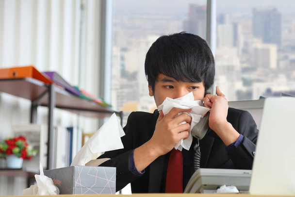 Business workers with flu and running nose in the office while answering phone call from customer during the coronavirus disease or covid-19 outbreak - Photo, Image