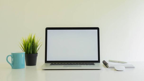 Ein Laptop und eine Graskaffeetasse mit Notizbuch auf dem Schreibtisch - Foto, Bild