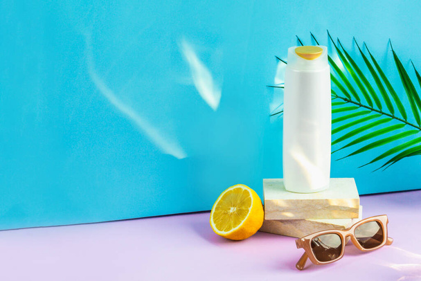 Hair cosmetics on a blue-purple background. an organic moisturizing shampoo sits on a granite-flagged podium, a wide-toothed comb for styling, and sunglasses lie next to it. - Foto, Imagem