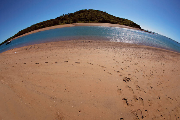 Voetafdrukken op het zand en een kreek met een boot, fisheye lens - Foto, afbeelding