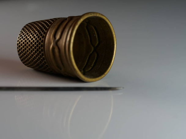 A needle and a vintage thimble on a grey background - Foto, Imagem