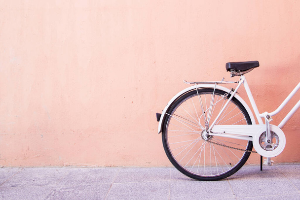 Zbliżenie białego roweru zaparkowanego przy brzoskwiniowej ścianie - idealne na estetyczne tapety - Zdjęcie, obraz