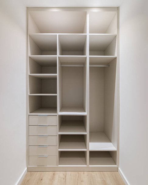 Новая встроенная мебель в маленькой гардеробной. Современное хранилище с гардеробом, много полок и ящиков - Фото, изображение