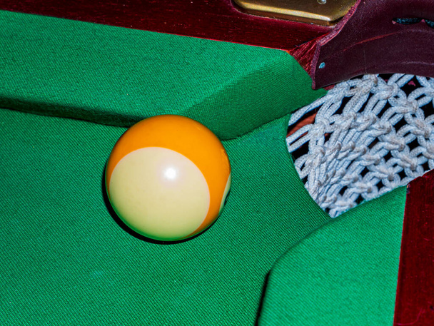 Labda a biliárdasztal zsebében. Lőj egy labdát. A biliárd zöld asztal zsebe. Szerencsejáték. Sport játék. Szabadidős tevékenységek. Üzlet. Háttér-kép. - Fotó, kép