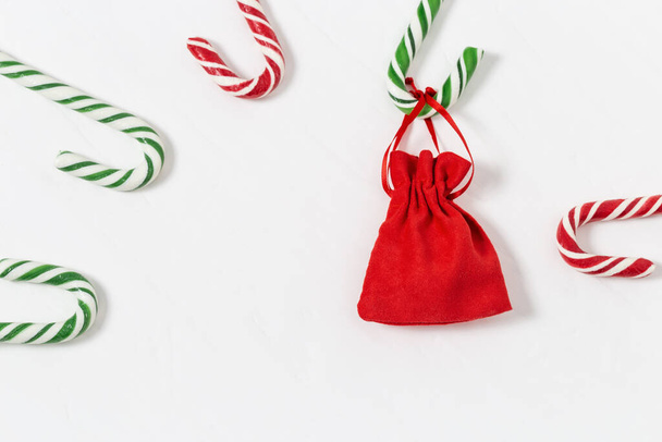 New Year gift on light background. Christmas gift. Red surprise bag. Candy canes and red gift. Flat lay. Copy space. - Fotó, kép