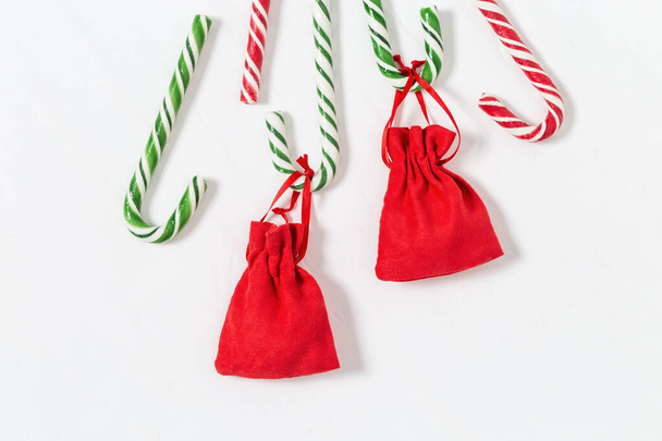 Christmas background with striped candy canes and gifts in small red bag. Christmas composition. Top view, copy space. - Foto, Imagen