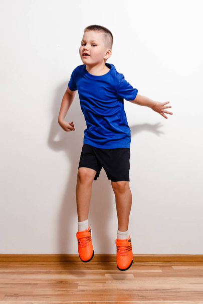 A seven-year-old short-haired boy jumps in sneakers against a white background. Children and sport - Valokuva, kuva
