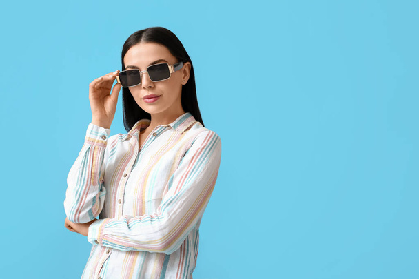 Schöne junge Frau trägt stylische Sonnenbrille auf farbigem Hintergrund - Foto, Bild