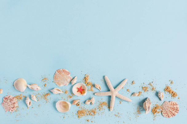 Seashells and beach sand on blue background top view. Sea summer background with copy space space. - Photo, Image