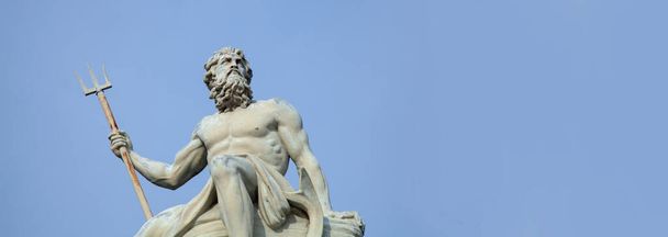 Potężny bóg morza i oceanów Neptun (Posejdon) Starożytny posąg na tle bleu.. Poziomy obraz. - Zdjęcie, obraz