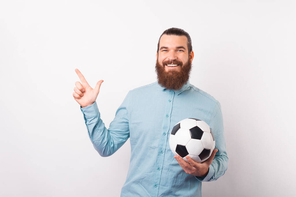Fotka muže držícího fotbalový míček a usmívajícího se do kamery ukazuje na volné místo . - Fotografie, Obrázek