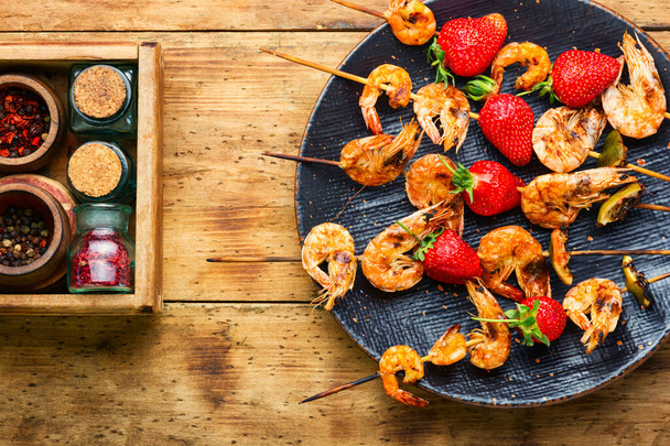 Tasty grilled shrimps on wooden skewers with strawberries.Roasted prawns,seafood - Photo, Image