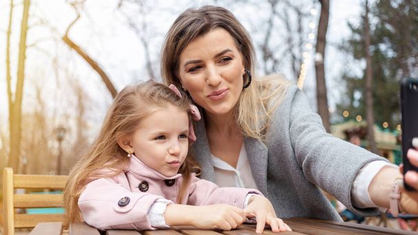 Happy mom and daughter taking selfie outdoors - Photo, image
