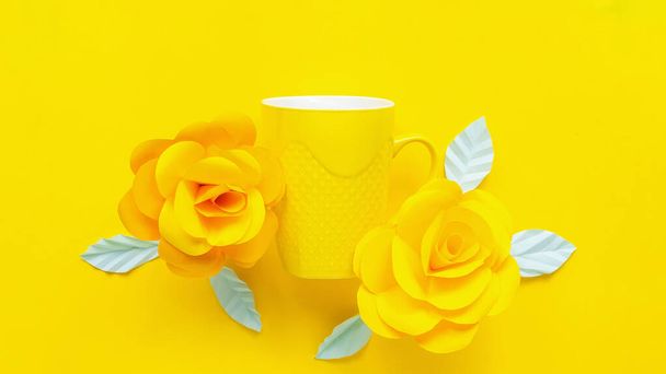 Fleurs artificielles jaunes et tasse jaune sur fond jaune - Photo, image